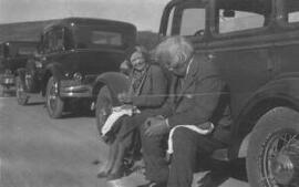 [David and Megan Lloyd George sitting on the running board of a car having a picnic]