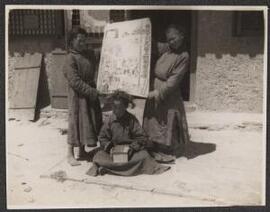 Three children with a sign 'Welcome to the Daban Lama Temple Meeting.'