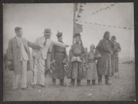 [A group of Mongolians in traditional dress alongside two men in Western dress]