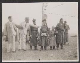 [A group of Mongolians in traditional dress alongside two men in Western dress]