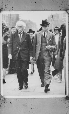 [David Lloyd George and A J Sylvester walking along a street]