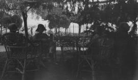 [Members of the Lloyd George entourage relaxing in a shaded garden]